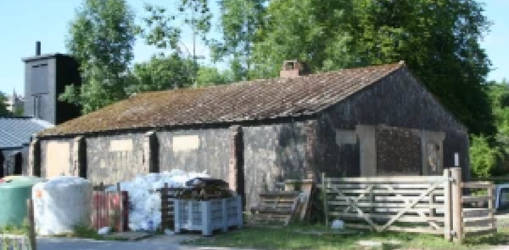 An our building of Defford Airfield a stone building with pallets and storage around it.